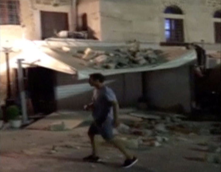 A man walks past a building damaged by a quake in Kos