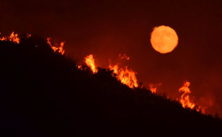 The full moon rises over flames of the Alamo fire on a hilltop off Highway 166 east of Santa Maria