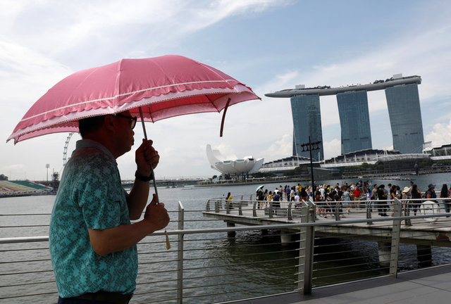 A tourist passes the Marina Bay Sands integrated resort on a hot day in Singapore