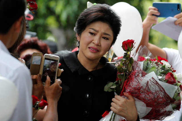 Ousted former Thai PM Yingluck Shinawatra greets supporters as she arrives at the Supreme Court in Bangkok