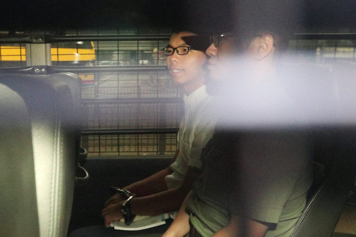 Democracy leader Joshua Wong sits in a prison van as he arrives at the High Court in Hong Kong