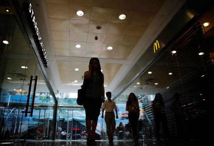 FILE PHOTO: A woman walks next to a McDonald's restaurant and a Starbucks coffee store at a shopping mall in Shanghai