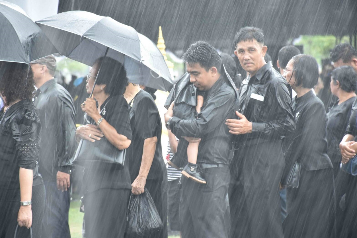 พสกนิกรเมืองคอนฝ่าสายฝนที่ตกหนักไม่ยอมหนี ยืนอุ้ม-จูงลูกรอถวายดอกไม้จันทน์