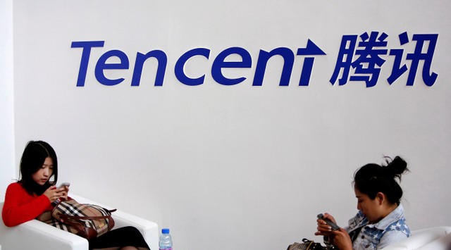 FILE PHOTO: Visitors use phones underneath of logo of Tencent at Global Mobile Internet Conference in Beijing