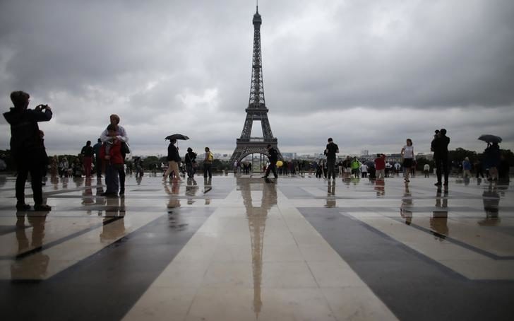 Tourists stroll on the Trocadero square in front of the Eiffel Tower in Paris
