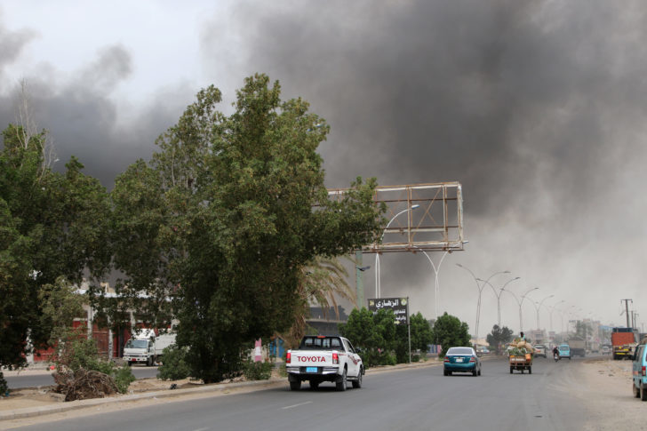 Smoke billows from a car parts store hit by shells during the conflict in the port city of Aden