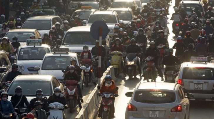 Motorists in their cars and on their motorcycles travel on a road in Hanoi