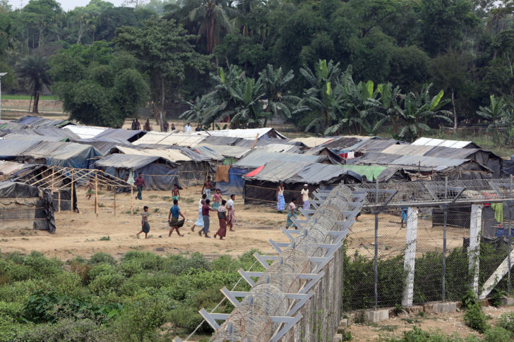 Rohingya people who fled from their towns after the violence in the state of Rakhine, are seen behind a fence on the border line outside Maungdaw