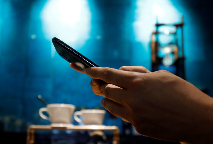 A man uses a mobile device in a coffee shop in Hanoi