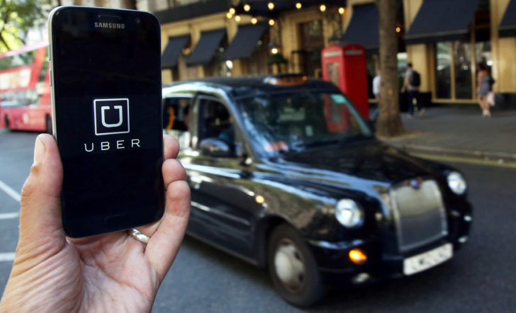 FILE PHOTO: A photo illustration shows the Uber app logo displayed on a mobile telephone, as it is held up for a posed photograph in central London.