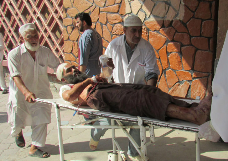 Afghan men carry an injured man to a hospital after a suicide attack in Nangarhar province
