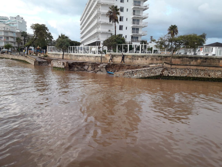 People walk along the damaged waterfront after a storm on the island of Mallorca