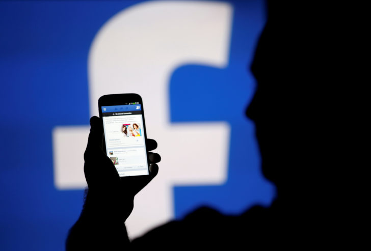 FILE PHOTO: A man is silhouetted against a video screen with an Facebook logo as he poses with an Samsung S4 smartphone in this photo illustration taken in the central Bosnian town of Zenica
