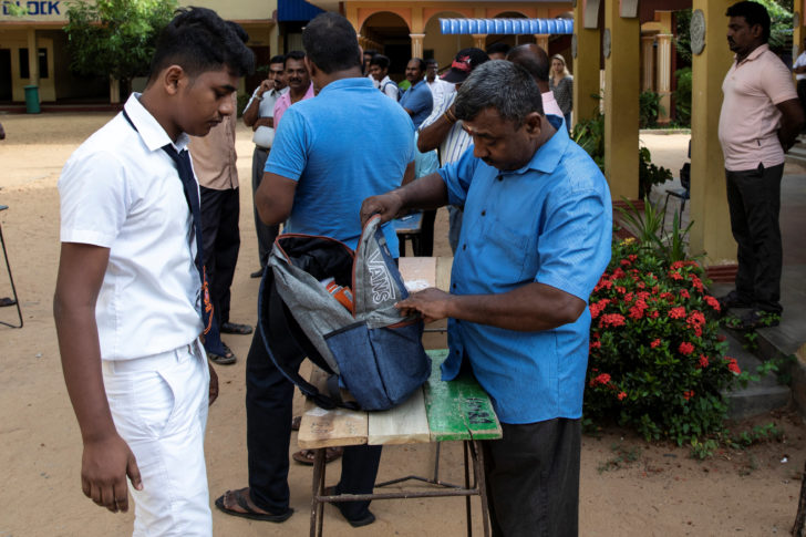 A student's bag is searched by a parent as he arrives at his school which opened days after a string of suicide bomb attacks across the island on Easter Sunday, in Batticaloa