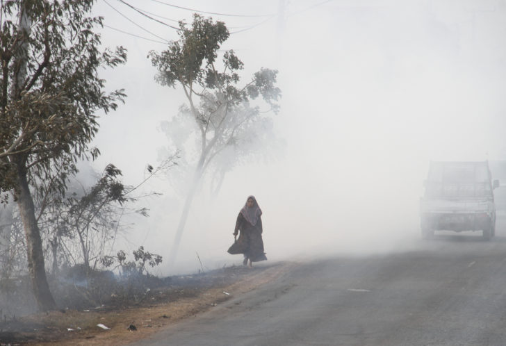 A woman walks along the road covered in smog due to the forest fire in Banjarbaru