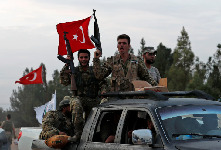 Turkey-backed Syrian rebel fighters drive on top of a truck to cross into Syria, near the border town of Akcakale