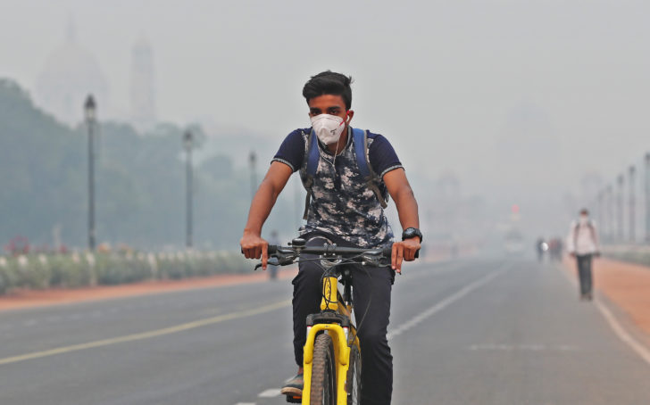 A man wearing a mask rides a cycle on a smoggy morning in New Delhi