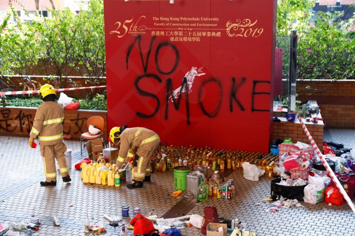 Firefighters examine debris left by protesters at the campus of the Polytechnic University (PolyU) in Hong Kong
