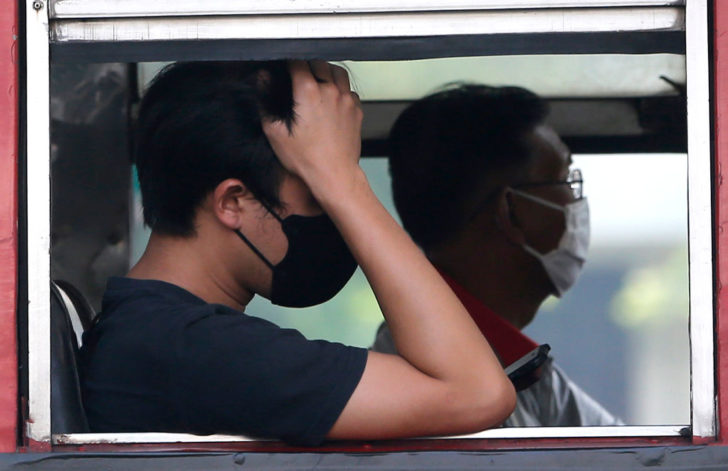 People sitting inside a open window bus seen wearing masks