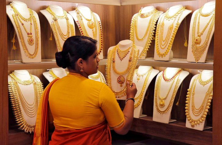 FILE PHOTO: A saleswoman picks gold necklaces to show to a customer inside a jewellery showroom in Kochi