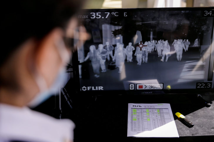 Airport personnel monitor a thermal scanner as passengers arrive at the Ninoy Aquino International Airport in Pasay