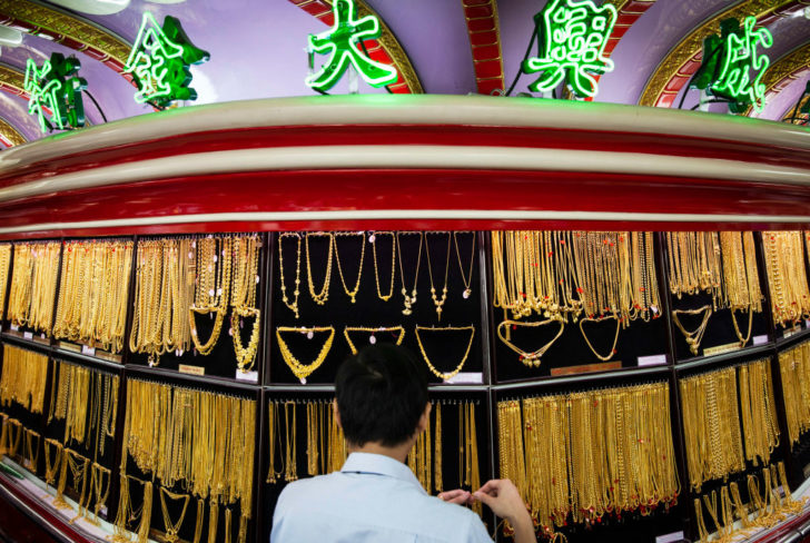A shop assistant organises a display of gold jewelry at the