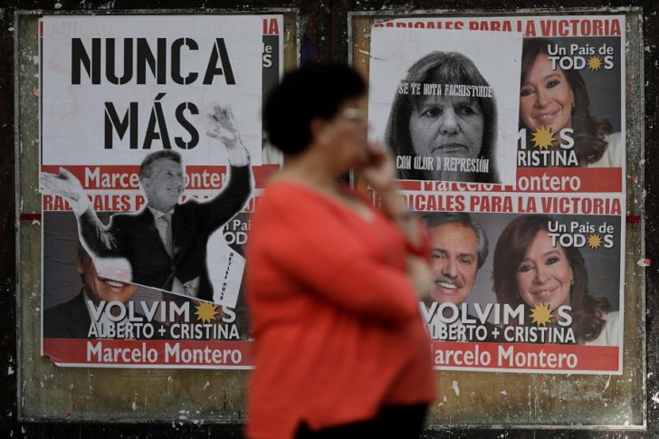 A woman stands near a wall covered in election posters one day after of the inauguration of Argentina's President Alberto Fernandez and his Vice President Cristina Fernandez de Kirchner in Buenos Aires, Argentina