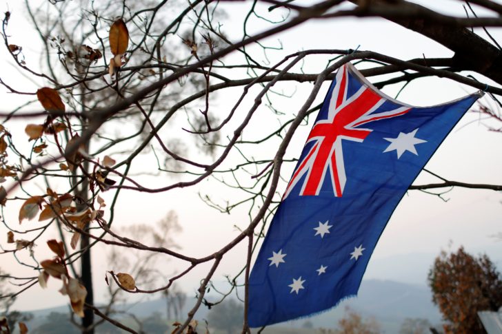 An Australian flag hangs from a burnt tree on the bushfire affected property of Jeff McCole, 70, in Buchan, Victoria, Australia