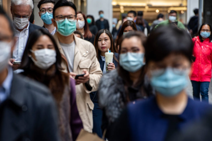 Pedestrians wear face masks in Central district of Hong Kong ไวรัสโคโรน่า สายพันธุ์ใหม่ 2019 และผลเบื้องต้นต่อเศรษฐกิจโลกและตลาด