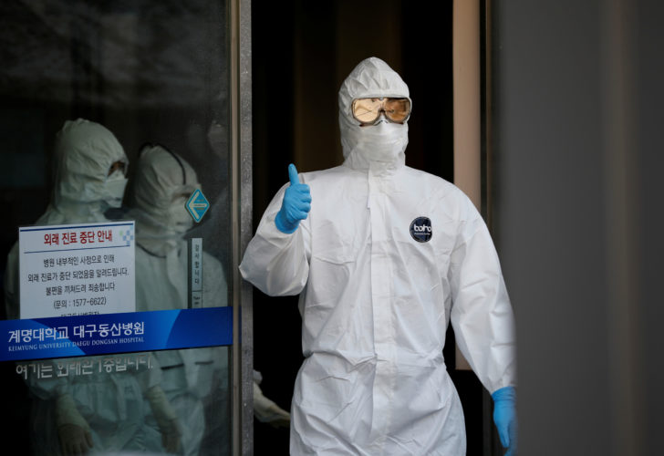 A medical worker gives a thumbs-up to media as he walks out of a facility where COVID-19 patients receive treatment at Keimyung University Dongsan Medical Center in Daegu
