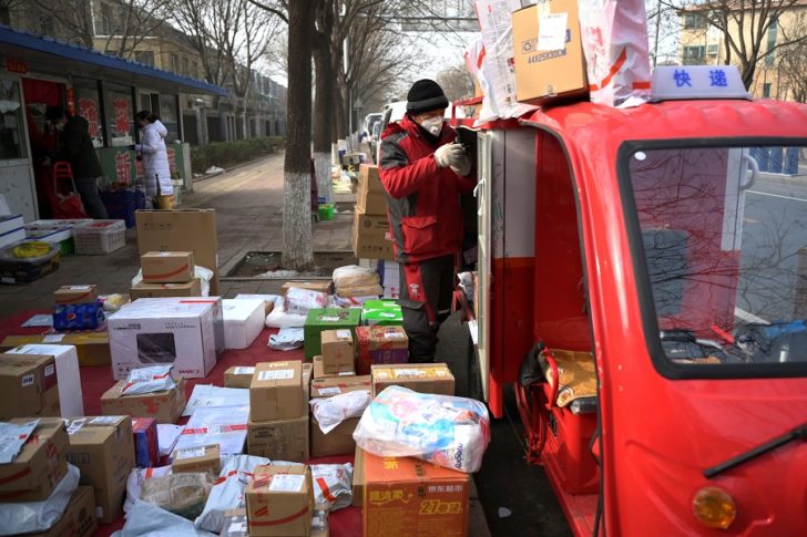 A JD.com delivery worker wearing a face mask unloads parcels outside a residential compound, as the country is hit by an outbreak of the novel coronavirus, in Beijing