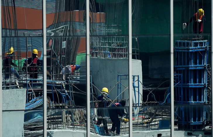 Thai labourers are reflected on glass pa