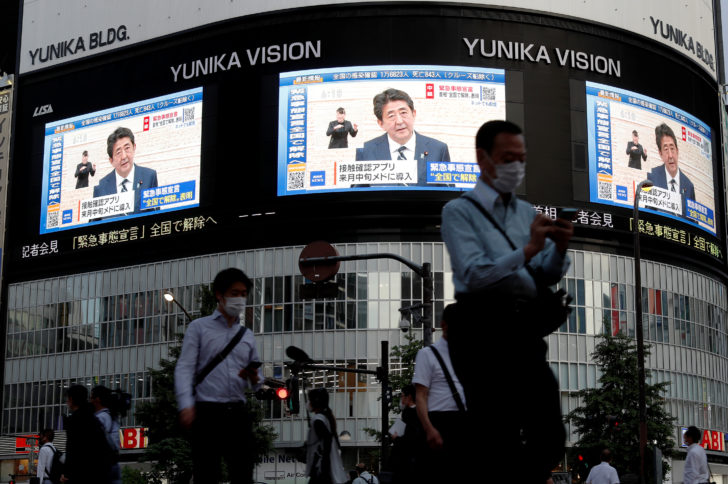 Large screens on a building show live broadcast of Japan's Prime Minister Shinzo Abe's news conference at Shinjuku district in Tokyo