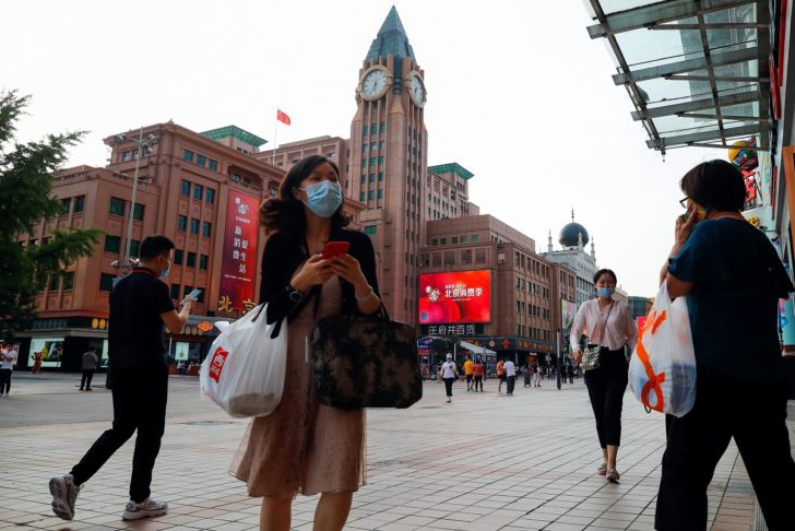 People walk past a department store of the Wangfuijing Group in Beijing