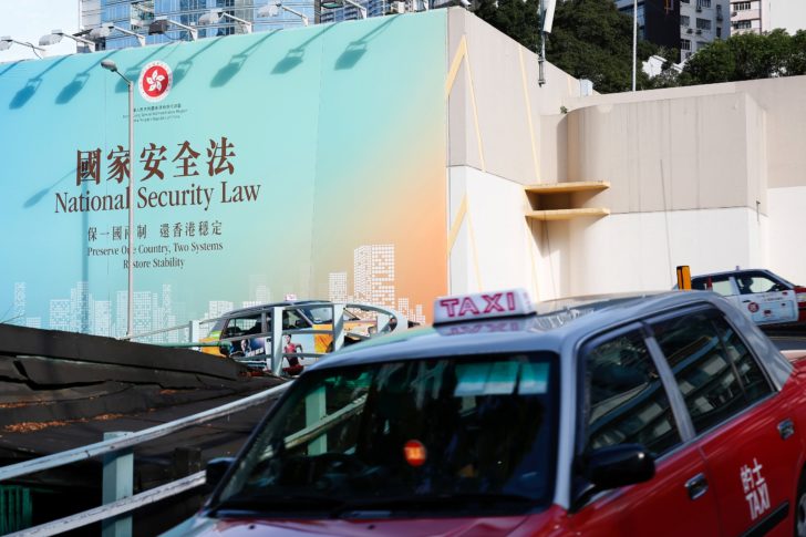 Taxis drive past government-sponsored advertisement promoting the new national security law during a meeting on national security legislation, in Hong Kong