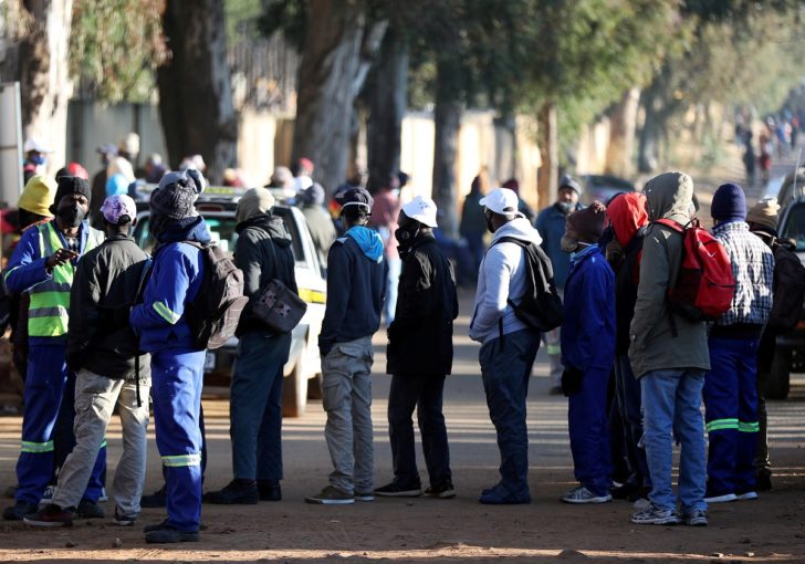 Job seekers stand outside a construction