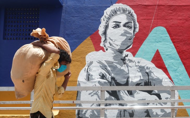 A man carrying a sack walks past a graffti of a healthcare worker during a lockdown to slow the spread of the coronavirus disease (COVID-19) in Mumbai