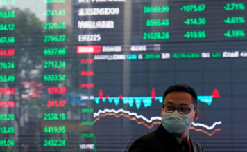 FILE PHOTO: A man wearing a protective mask is seen inside the Shanghai Stock Exchange building, as the country is hit by a new coronavirus outbreak, at the Pudong financial district in Shanghai