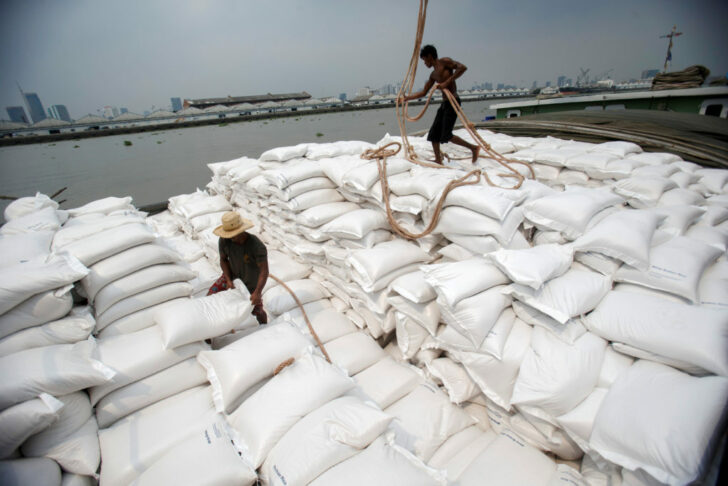 FILE PHOTO: Immigrant workers unload sacks of rice from a barge to a cargo ship on the Chao Phraya River in Bangkok