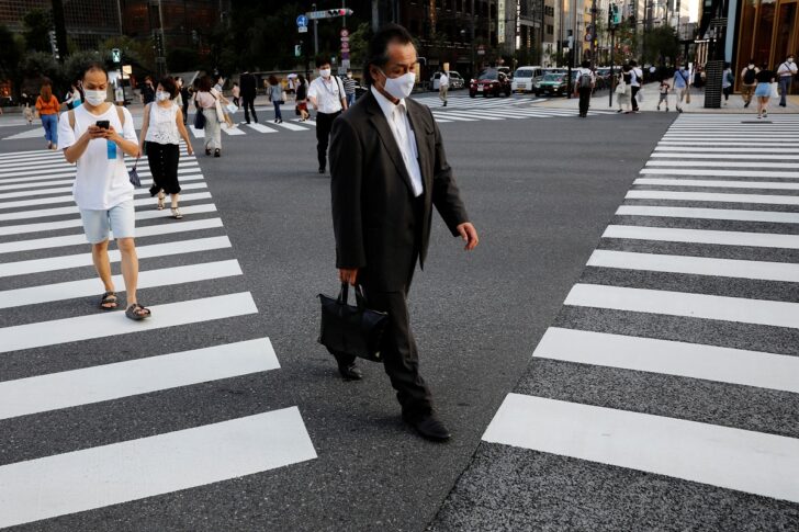 People wearing protective masks make their way at a business district in Tokyo คนญี่ปุ่น