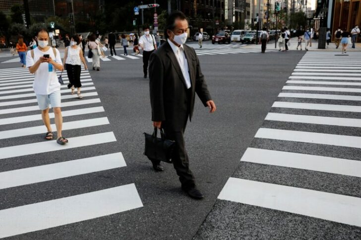 People wearing protective masks make their way at a business district in Tokyo