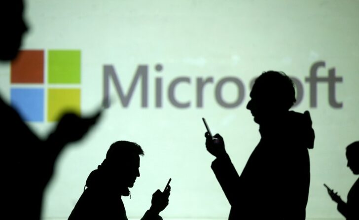 FILE PHOTO: FILE PHOTO: FILE PHOTO: Silhouettes of mobile users are seen next to a screen projection of Microsoft logo in this picture illustration