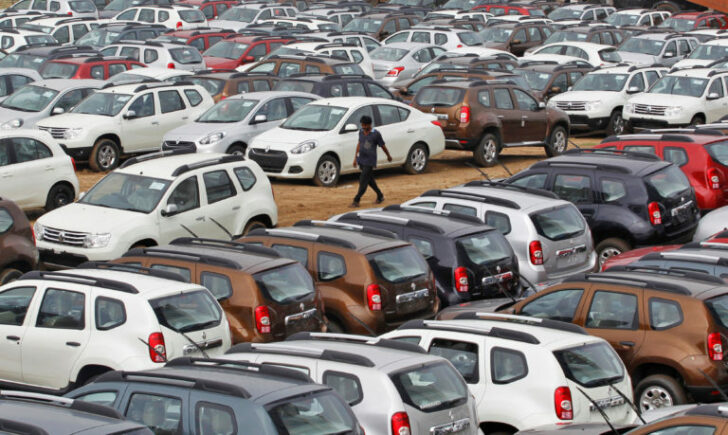 FILE PHOTO: A worker walks past parked Renault cars at its stockyard on the outskirts of Ahmedabad