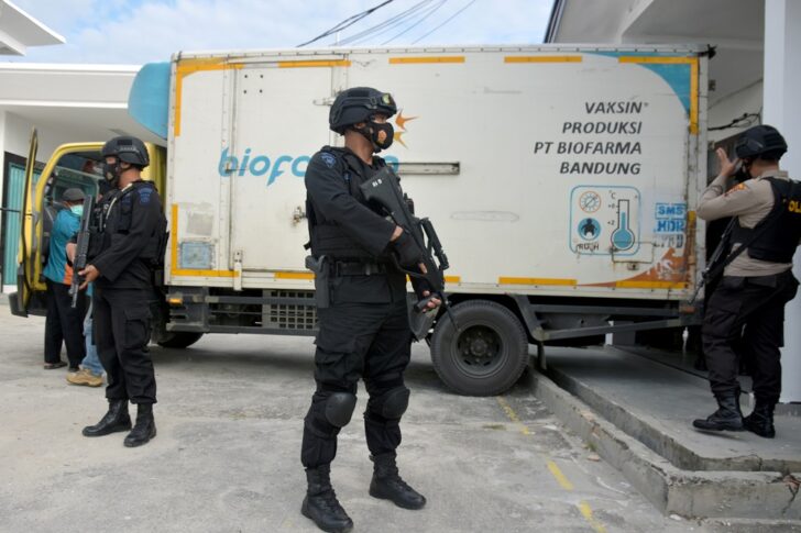 Armed police officers stand guard next to a truck containing Sinovac's vaccine for coronavirus disease (COVID-19) during its distribution in Pekanbaru