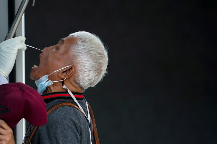 A healthcare worker takes a nasal swab sample from a local resident for a COVID-19 test in Bangkok