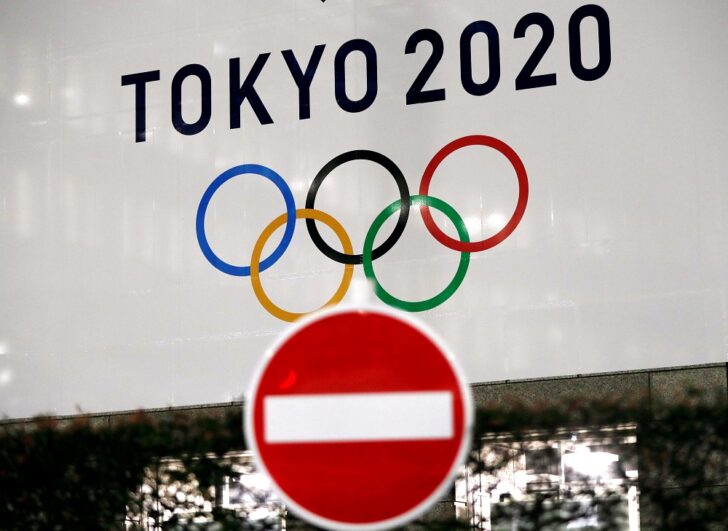 FILE PHOTO - A banner for the upcoming Tokyo 2020 Olympics is seen behind a traffic sign, following an outbreak of the coronavirus disease (COVID-19), in Tokyo