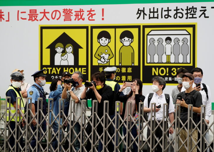 People take photos from outside a lighting ceremony at the Tokyo 2020 Olympic torch relay celebration in Tokyo