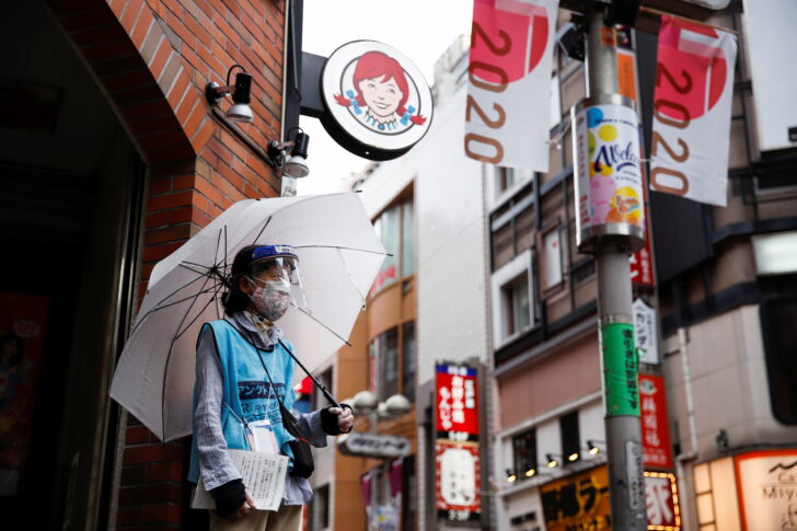 Woman who does street surveys wears a mask and face shield, in Tokyo