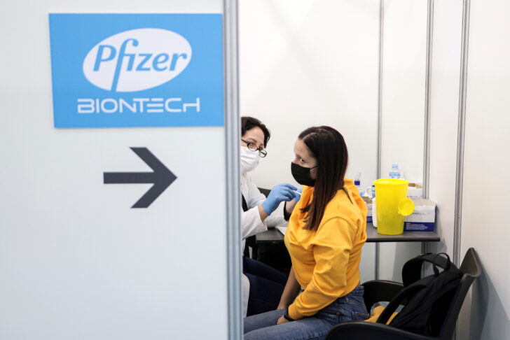 FILE PHOTO: A healthcare worker administers a dose of Pfizer's coronavirus disease (COVID-19) vaccine to a woman at Belgrade Fair vaccination center in Belgrade