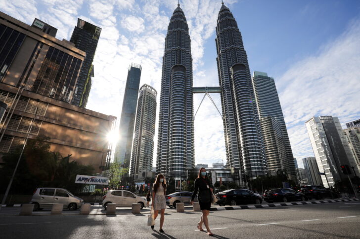 FILE PHOTO: People wearing protective masks cross a street in front of Petronas Twin Towers, amid the coronavirus disease (COVID-19) outbreak in Kuala Lumpur